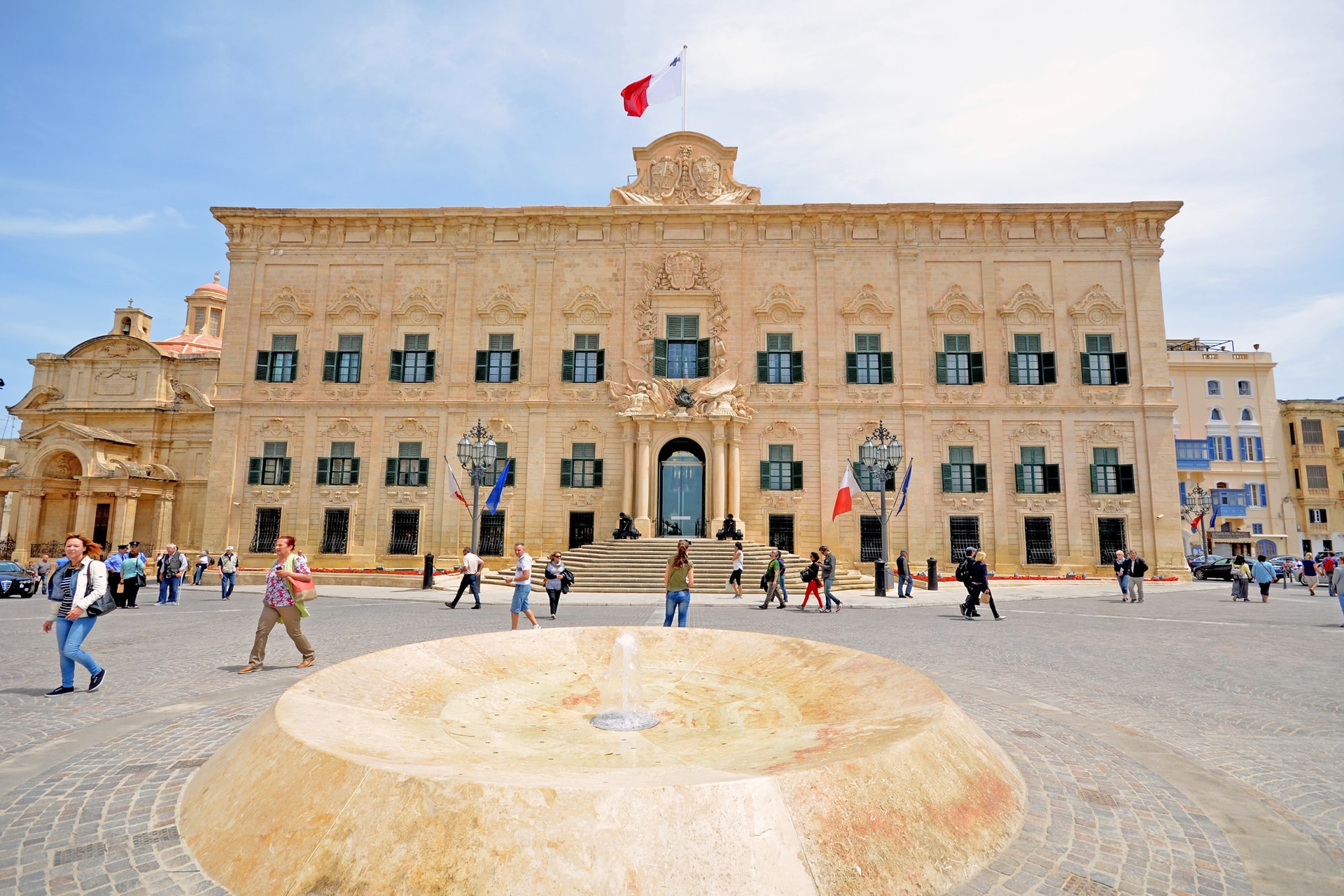 Fassade des Großmeisterpalasts in Valletta mit springendem Brunnen und Menschen auf dem Platz