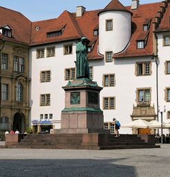 Bronzestatue von Friedrich Schiller vor historischen Gebäuden