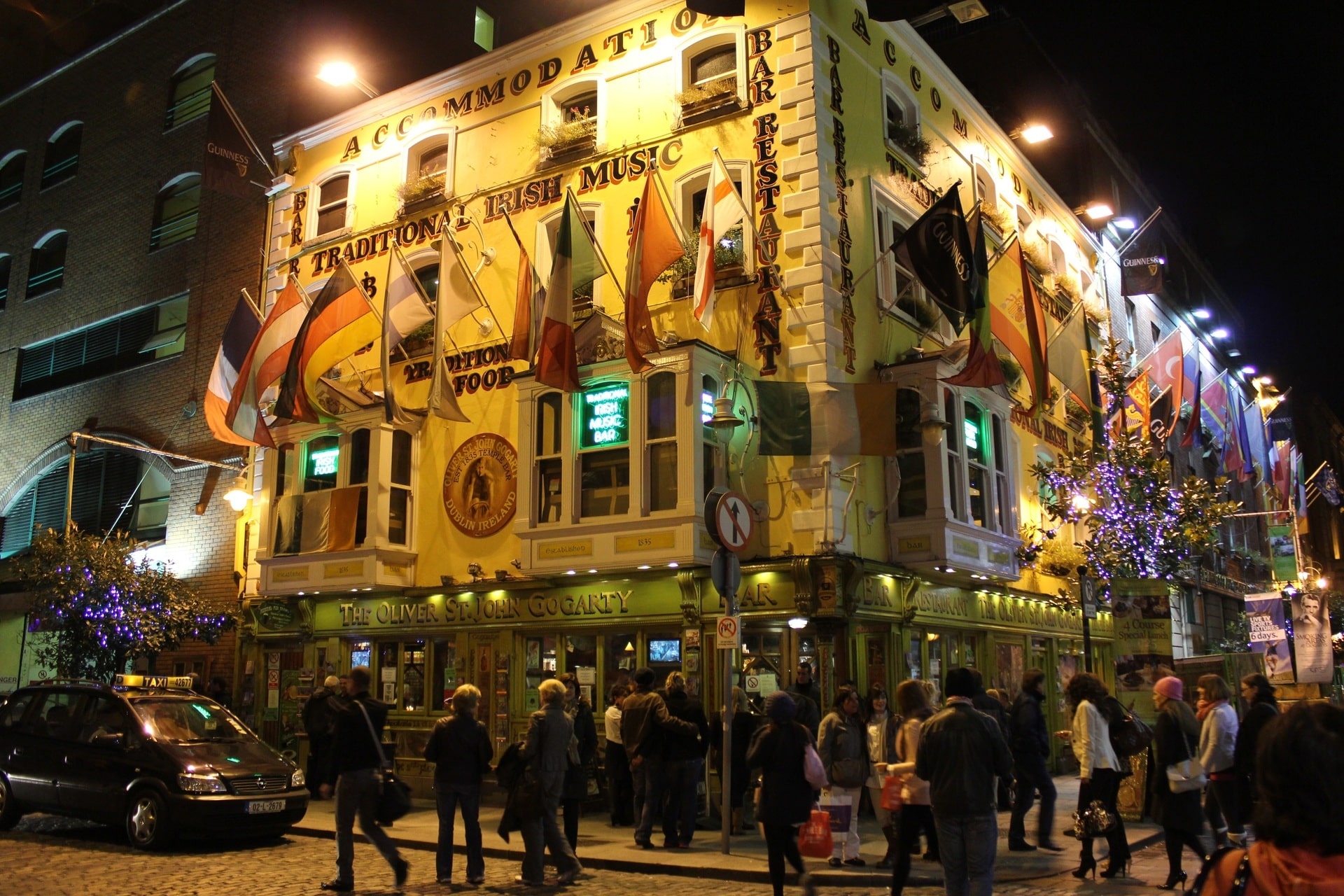 Belebter Pub mit Fahnen und Menschen im nächtlichen Straßenlicht