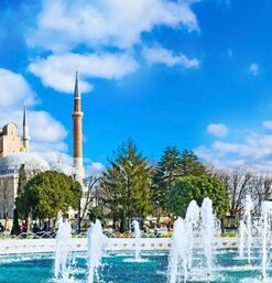 Blick auf die Hagia Sophia in Istanbul mit Minaretten und vorgelagertem Springbrunnen bei blauem Himmel