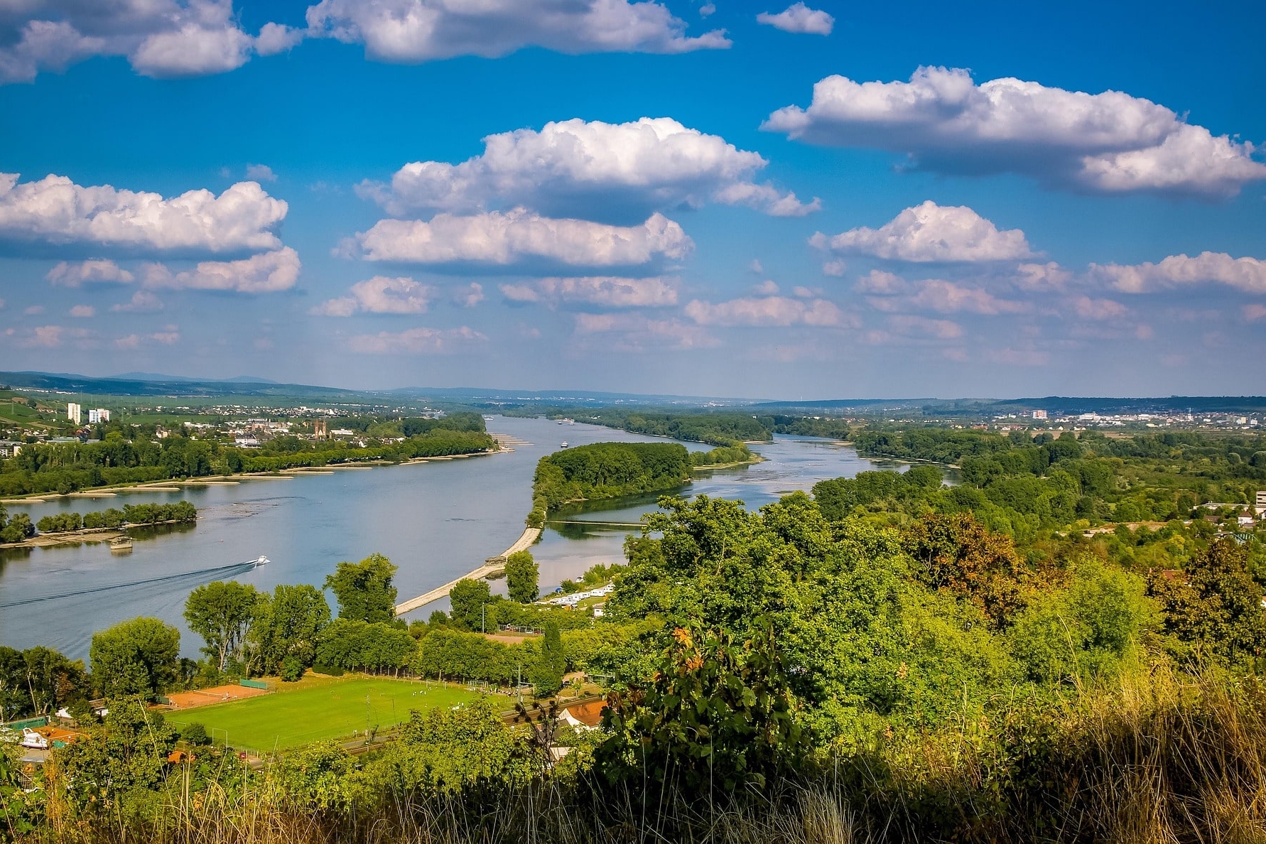 Breiter Fluss mit grünen Uferlandschaften und Wolkenhimmel