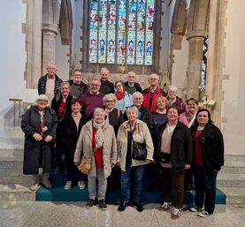 Teilnehmergruppe der Irlandreise in der anglikanischen Kathedrale von Cork mit buntem Glasfenster im Hintergrund