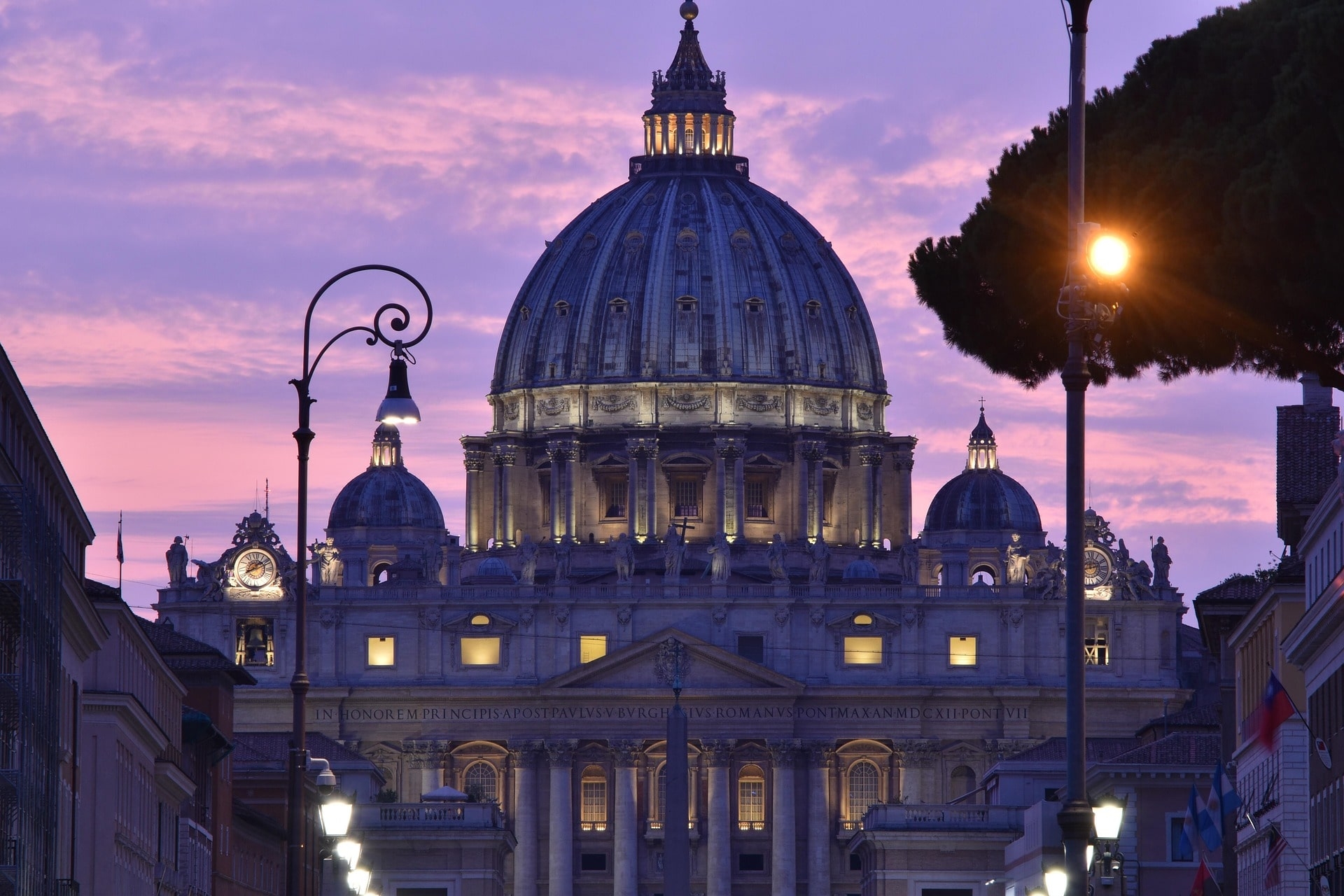 Beleuchtete Kuppel des Petersdoms vor violettem Himmel