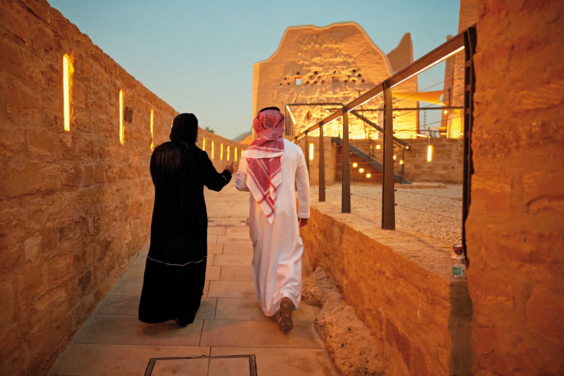 Paar in traditioneller Kleidung in beleuchteter Lehmziegel-Gasse der Altstadt Al-Turaif, Saudi-Arabien