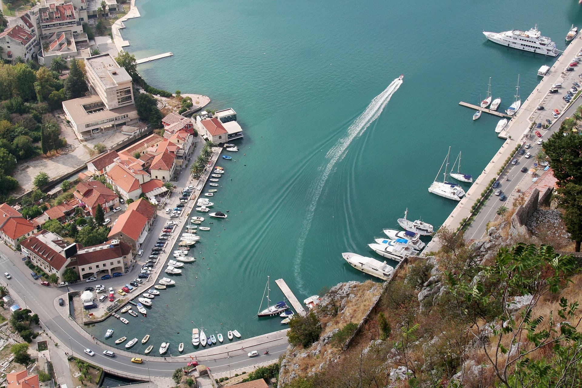 Yachthafen mit Booten und roten Dächern am türkisblauen Wasser