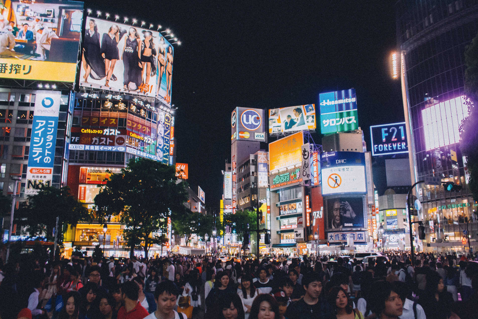Menschenmenge bei Nacht an der Shibuya-Kreuzung in Tokio mit Leuchtreklamen