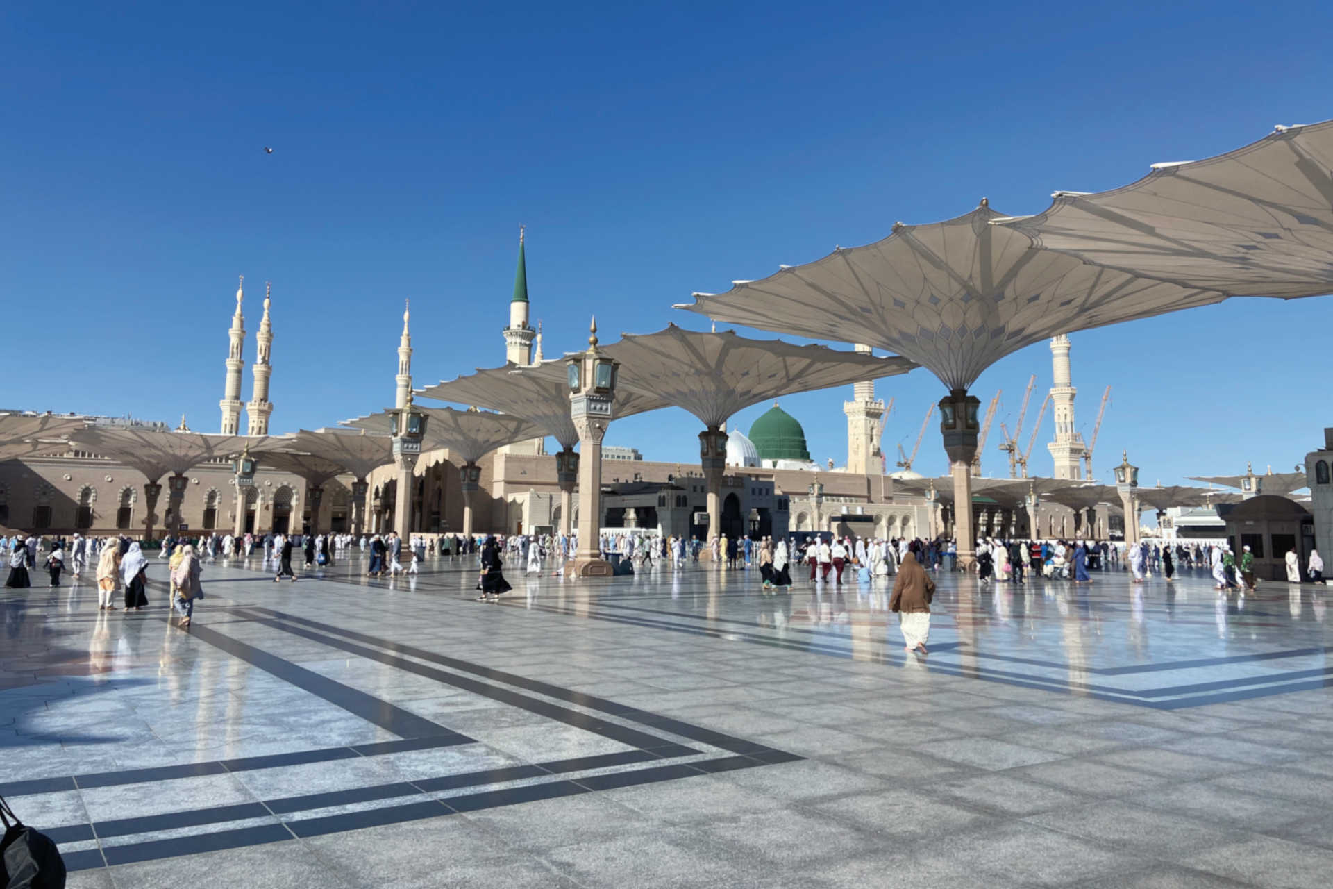 Pilger auf dem Vorplatz der Al-Masjid an-Nabawi mit markanten Schirmen und grün-goldener Kuppel