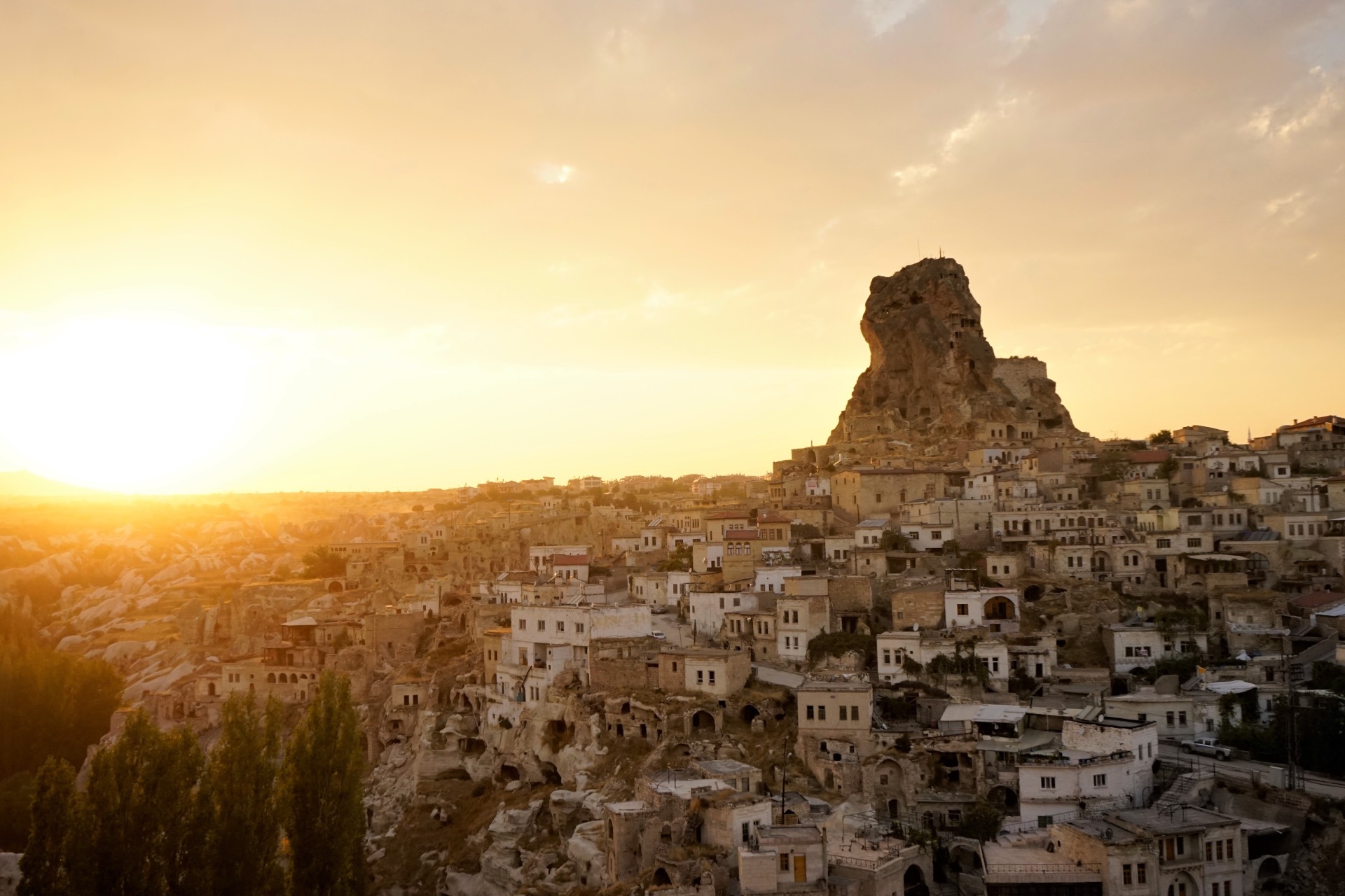 Höhlenhäuser und Tufffelsen im Abendlicht mit goldgelbem Sonnenuntergang